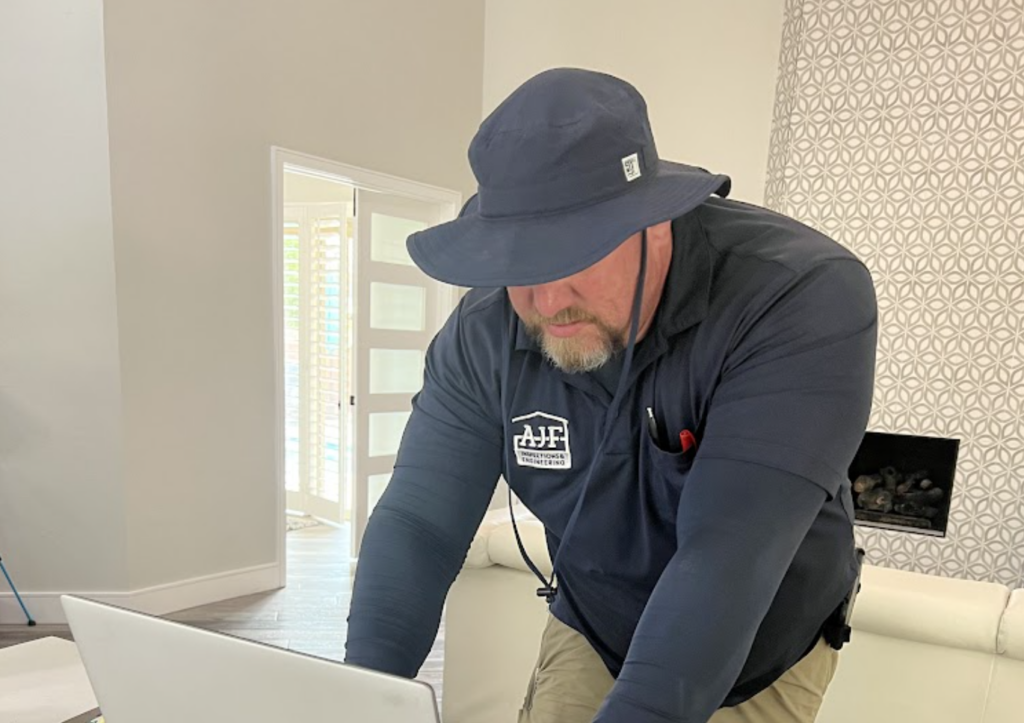 AJF inspector on the computer at the kitchen island documenting warranty inspection results